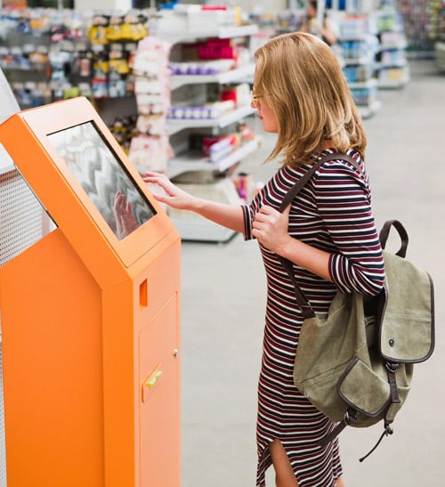 Woman using a kiosk with printer in a retail environment