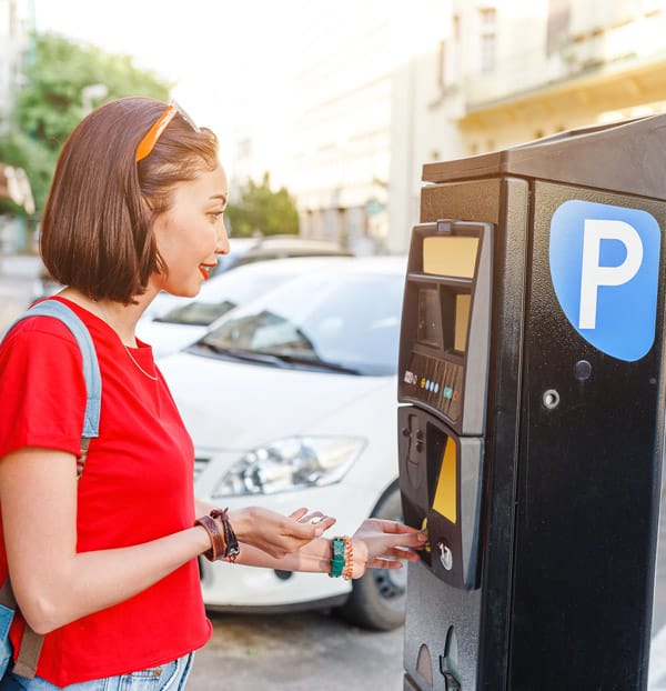 Woman paying at a parking-meter to get a ticket