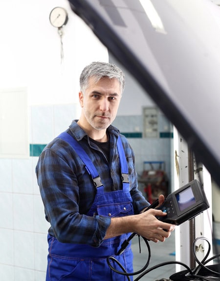 A mechanic performing a vehicle diagnostic thanks to a device